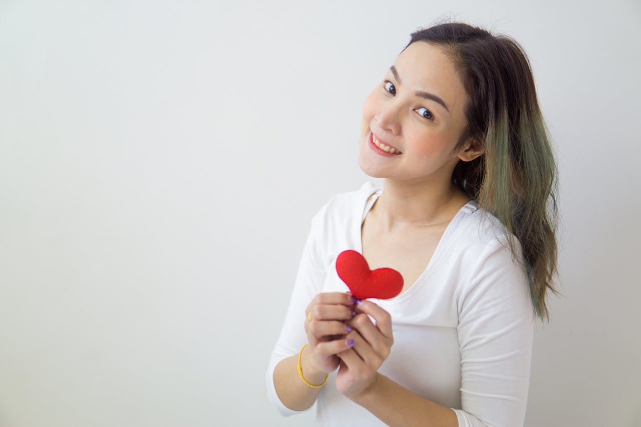 why-choose-us A cheerful woman in white holds a red heart, embodying love and wellness.